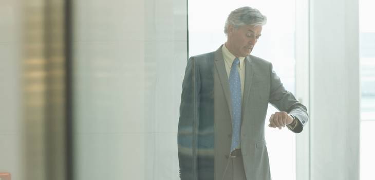 Middle-aged man in a suit looking at his watch