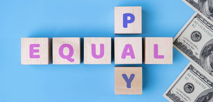 Colored wooden cubes laid flat on a table, spelling out "Equal Pay"