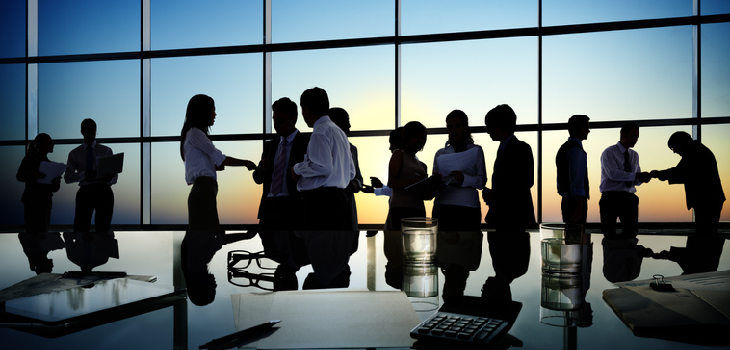 An office meeting in dim lighting, with a sunset in the background