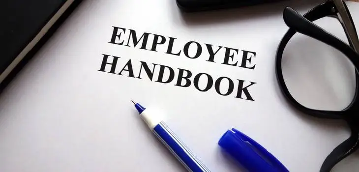 Employee handbook with a pen by its side